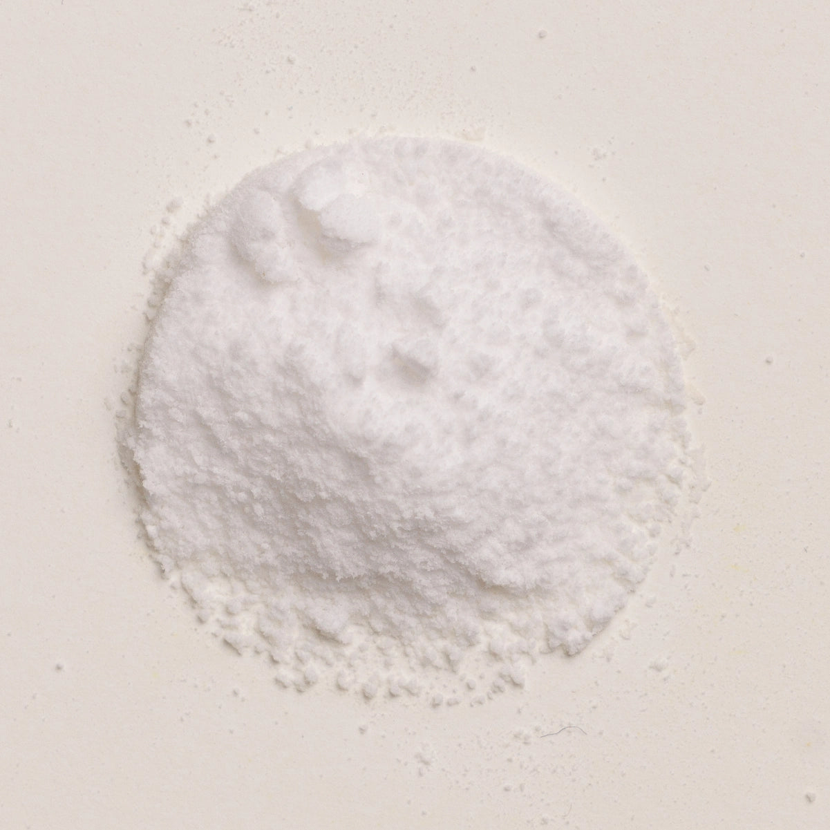 A small mound of white choline bitartrate powder on a plain light beige background.